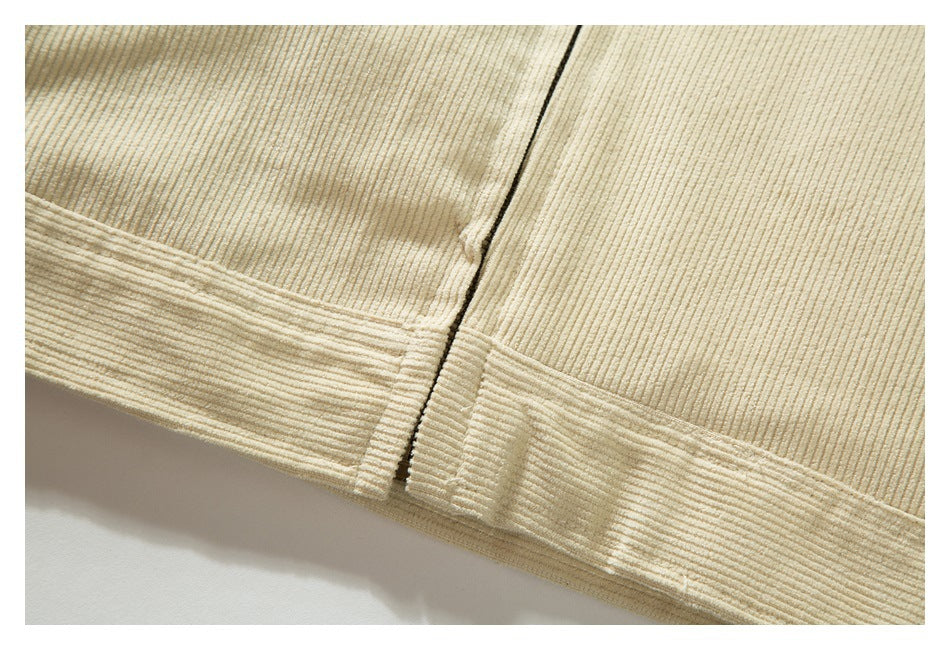 Close-up of the cream jacket's ribbed fabric and stitched lower hem.