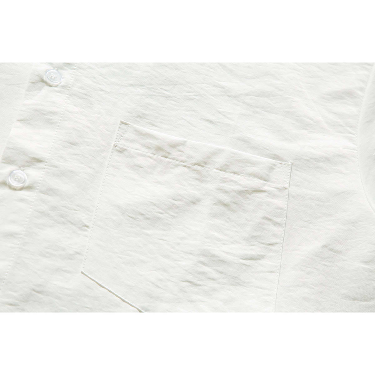 Close-up of an ivory shirt's chest pocket, placket, and two white buttons.