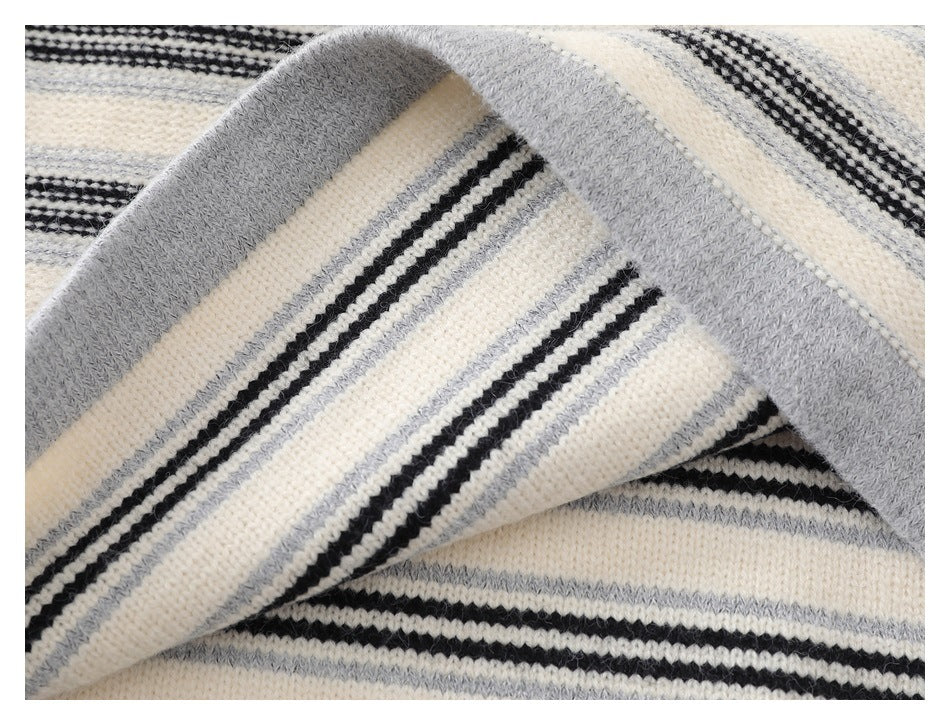 Close-up of a folded gray ribbed cuff and striped sleeve on the cream sweater.