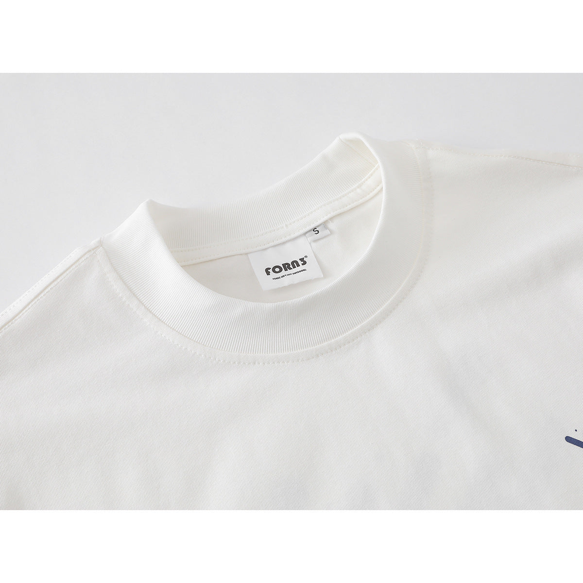 Close-up of a white T-shirt’s ribbed crew neck, shoulder seam, and inner neck label.