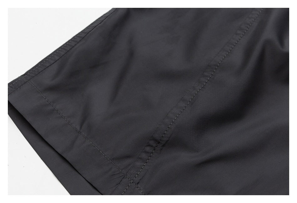Close-up of black shorts showing a stitched panel seam and finished edge.