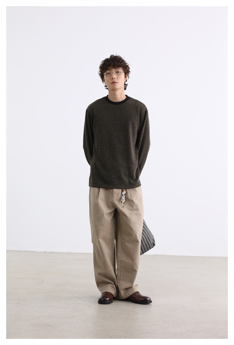 Model wearing a dark brown ribbed long-sleeve crewneck top with a black collar and beige trousers.