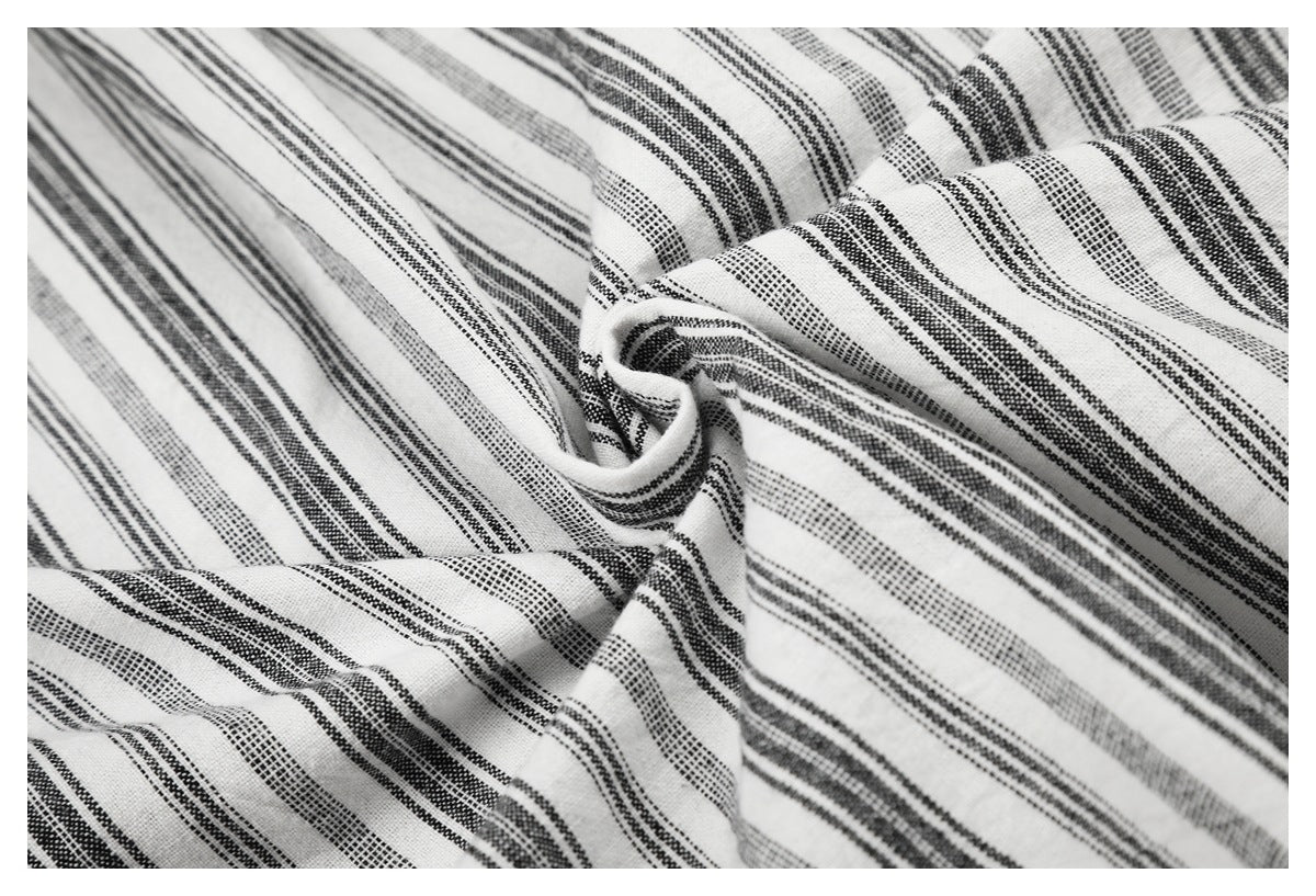 Close-up of white fabric with black and gray stripes gathered into soft folds.