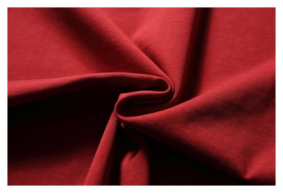Close-up of deep red fabric folded into soft folds, showing a fine knit-like surface texture.