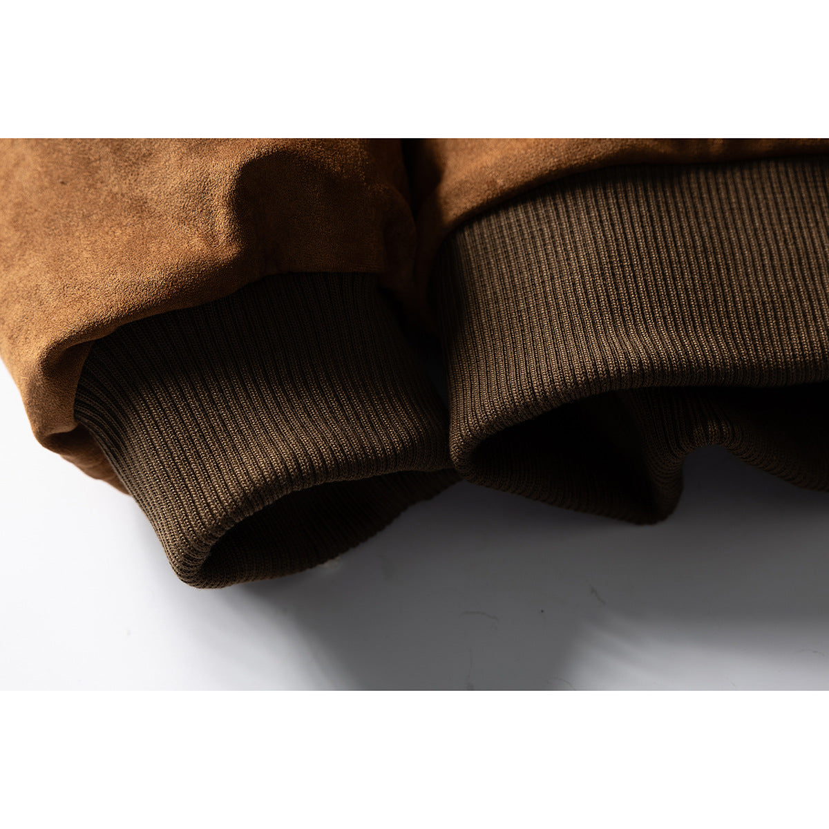 Close-up of the brown jacket's dark ribbed knit cuff and brown outer fabric.