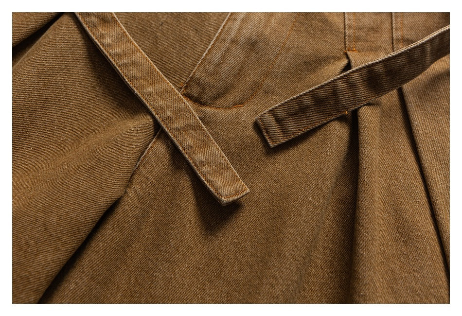 Close-up of tan trouser fabric with overlapping belt loops and a waistband seam.