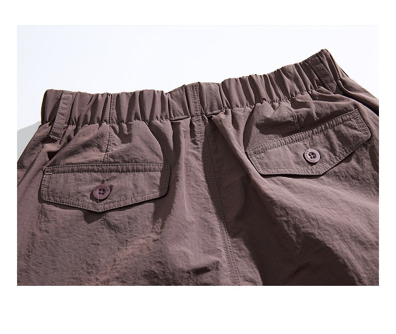 Close-up of the back of brown shorts with an elastic waistband and two buttoned flap pockets.