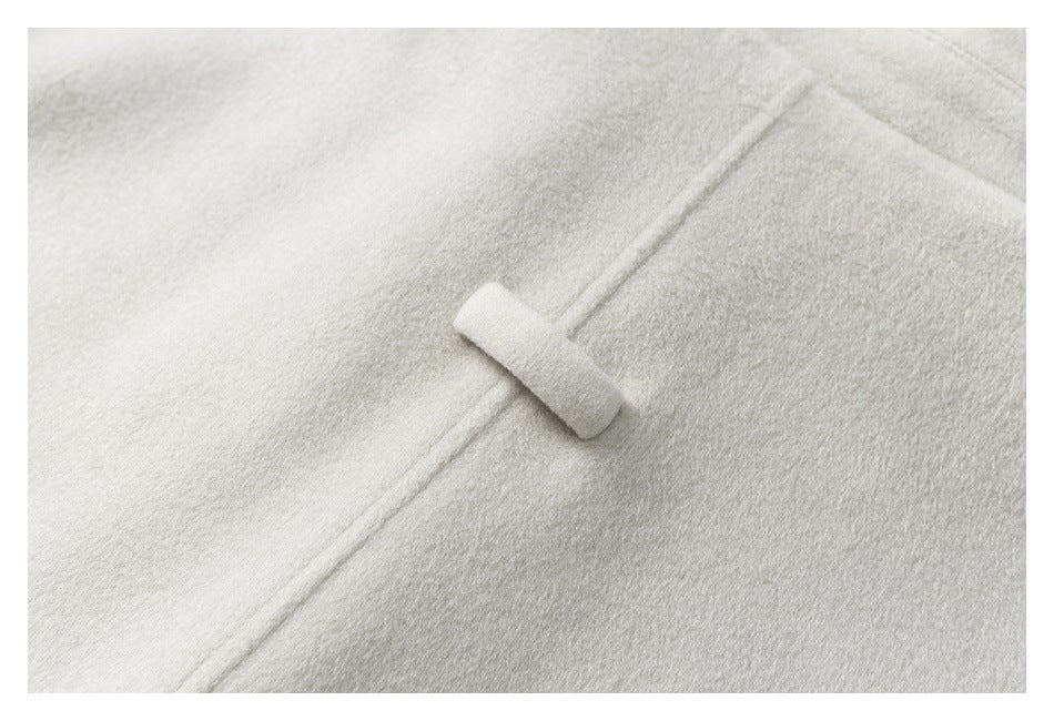 Close-up of a small fabric tab fastening on the off-white coat.