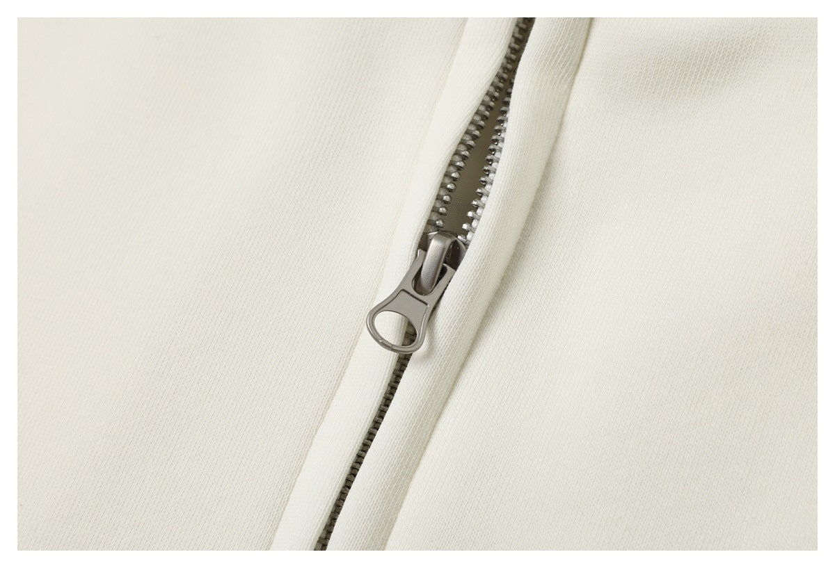 Close-up of the metal zipper and pull against ivory jacket fabric.