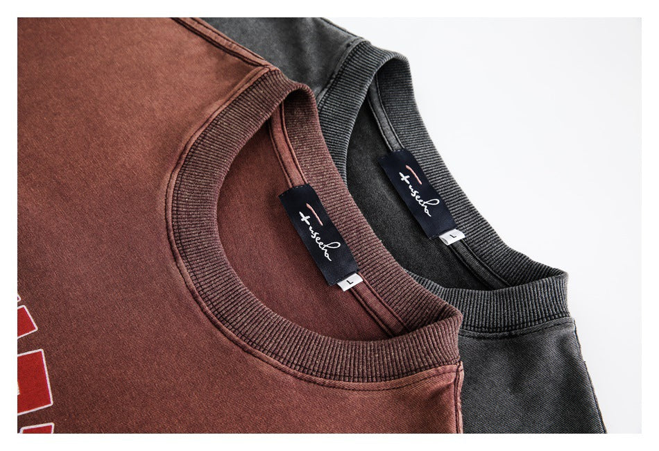 Close-up of rust-brown and charcoal crewneck sweatshirts showing ribbed collars and sewn-in neck labels.