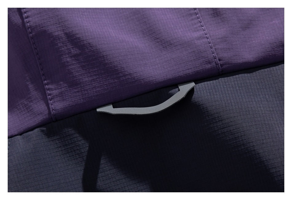 Close-up of a curved gray pull tab at the edge of a purple and dark navy jacket panel.