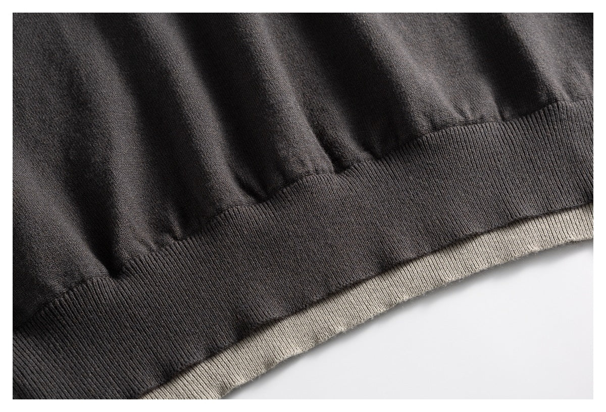 Close-up of the charcoal sweater's ribbed hem, with a narrow taupe layer visible underneath.