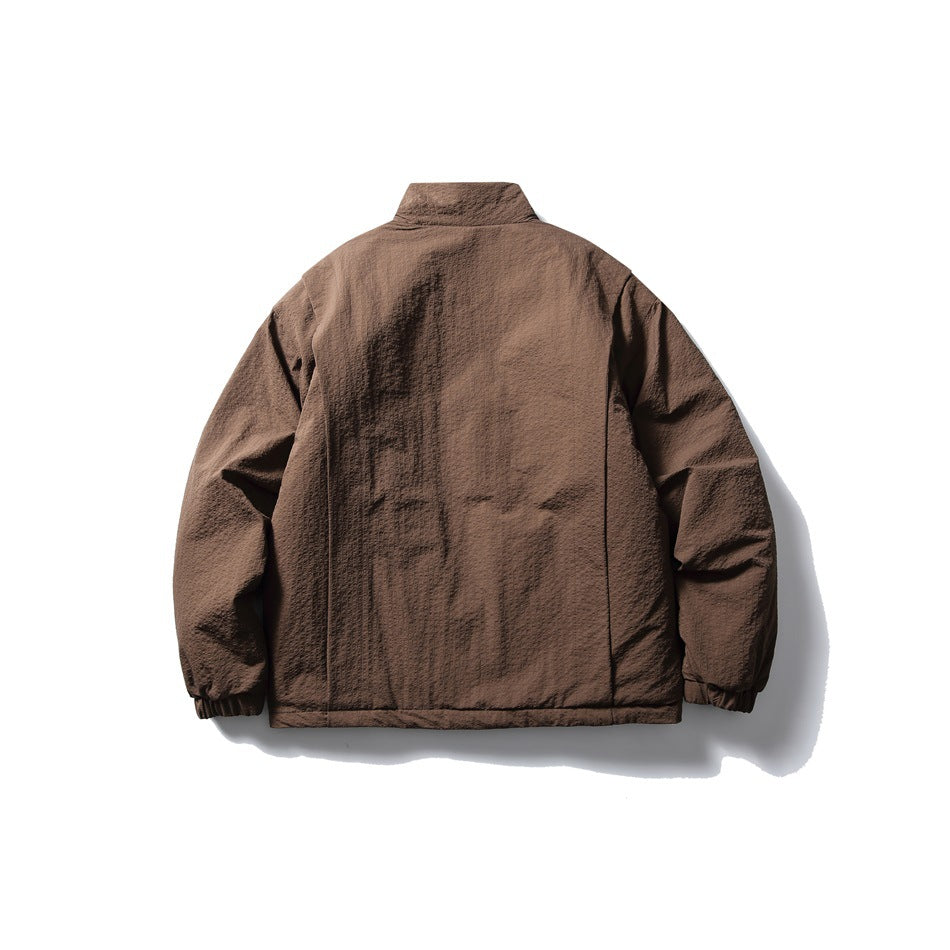 Back view of a brown jacket laid flat, with a stand collar, long sleeves, and elasticated cuffs.