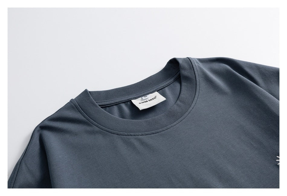 Close-up of the dark slate blue T-shirt’s ribbed crew neck and inner label.