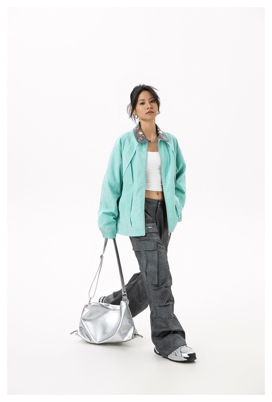Full-length view of a model wearing an open mint jacket with an embroidered gray collar and dark cargo pants.