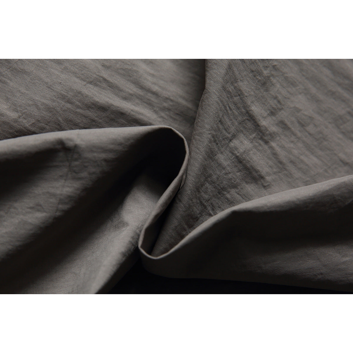 Close-up of the gray shorts fabric, showing its fine texture and folded construction.