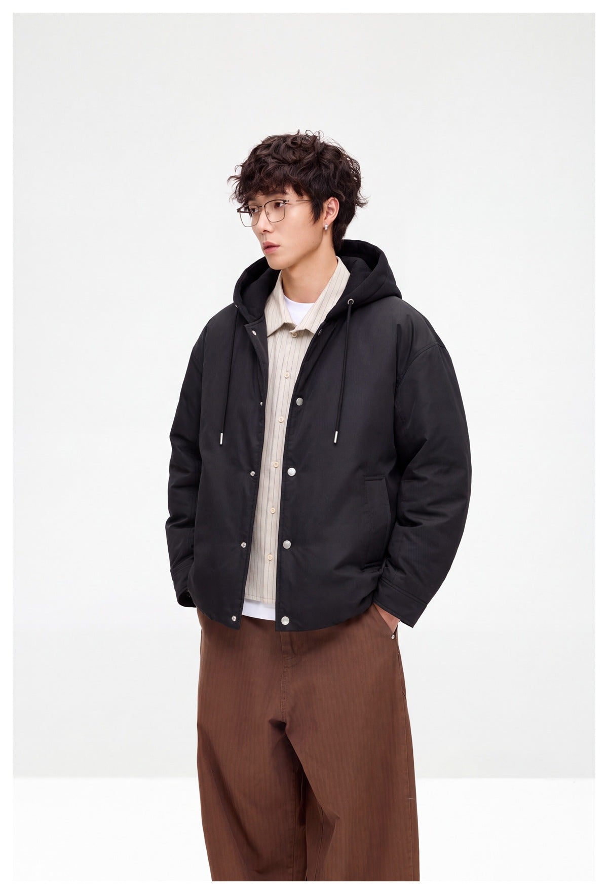 Model in a black hooded snap-front jacket, shown from a three-quarter front angle.