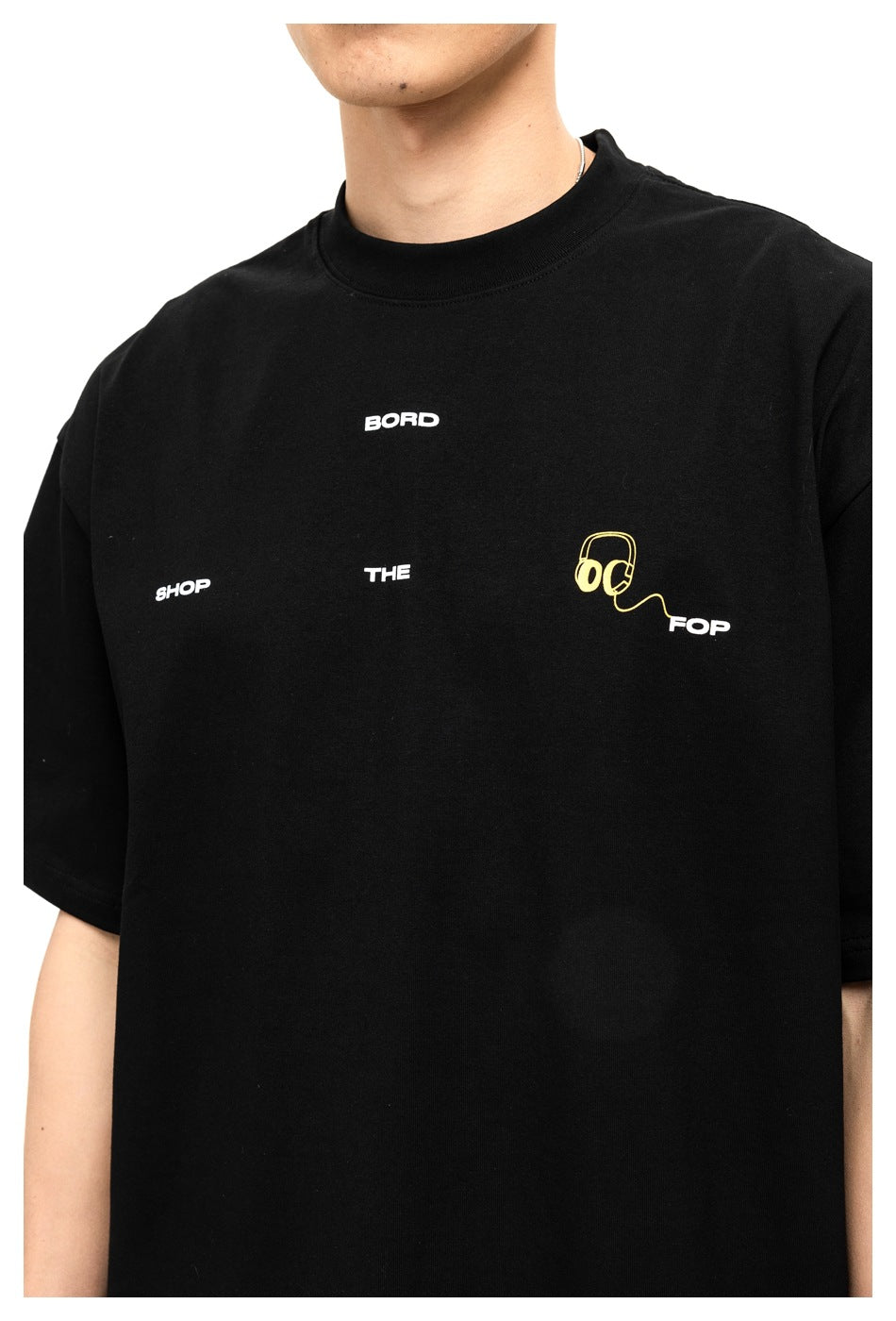 Close-up of a black T-shirt with white lettering and a yellow headphone graphic across the chest.