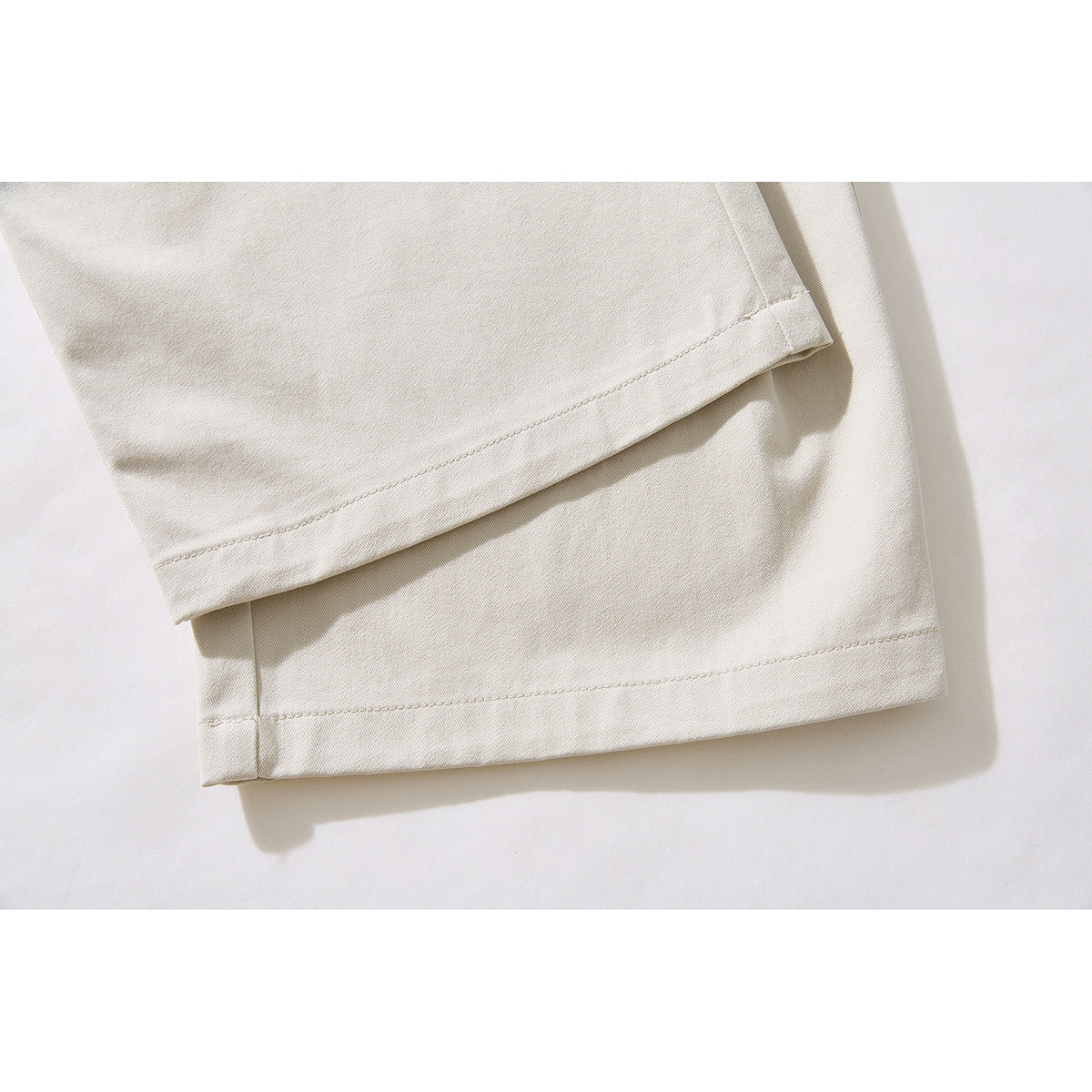 Close-up of the stitched hems on ivory wide-leg pants.