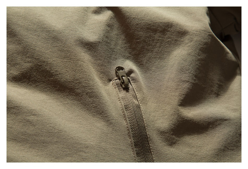 Close-up of a zipper on olive-khaki garment fabric.