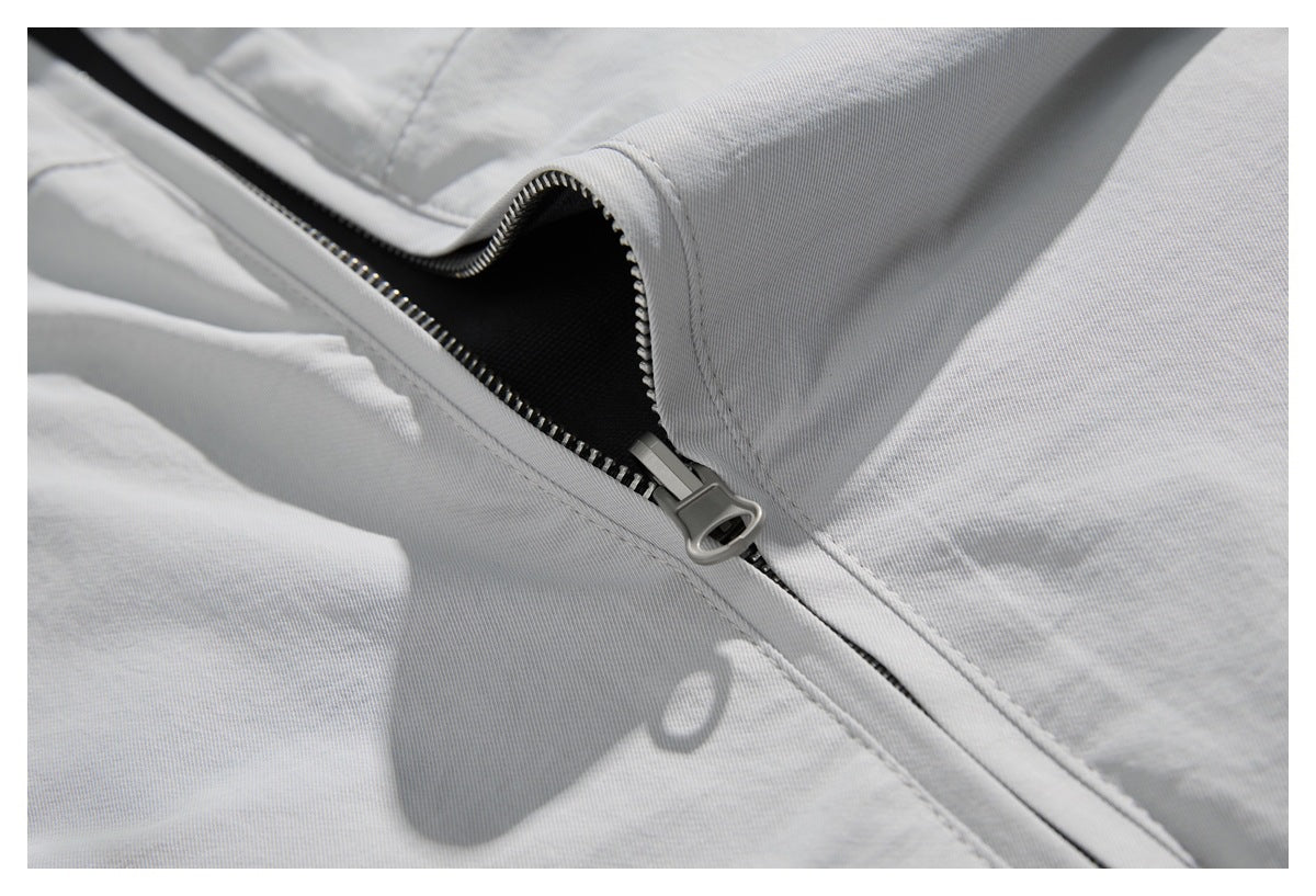 Close-up of a partially open zipper on a light gray garment, revealing dark lining.