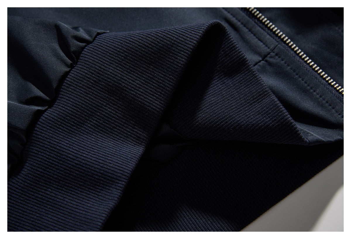 Close-up of a dark navy jacket with a ribbed cuff and a metal zipper.