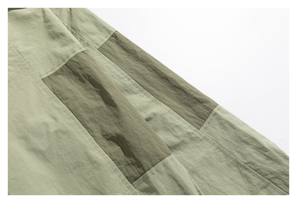 Close-up of olive-green garment panels with darker contrasting strips and visible stitching.