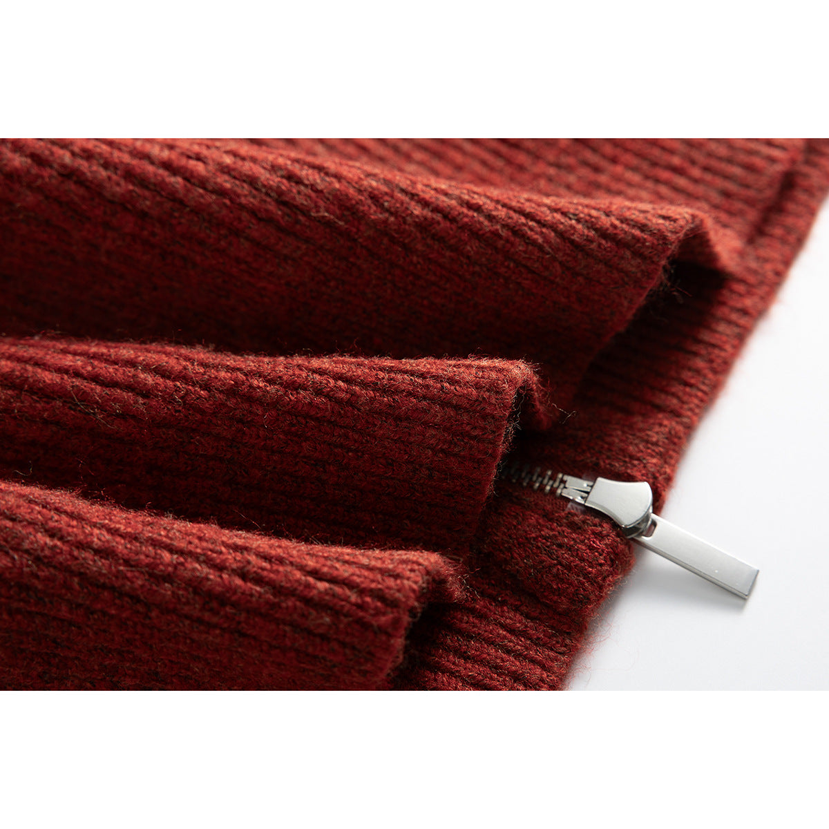 Close-up of the rust-red ribbed sweater’s silver zipper and knit front placket.
