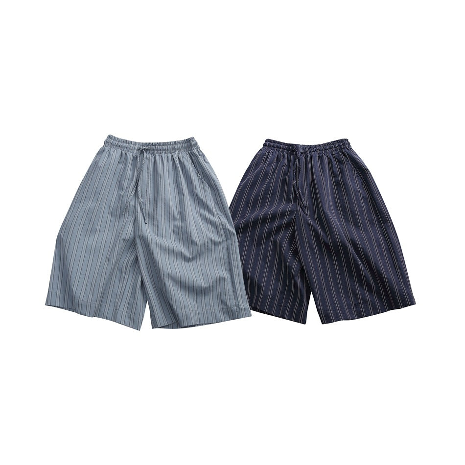 Two pairs of loose pinstriped shorts laid flat: one light gray and one navy, both with elastic waistbands.