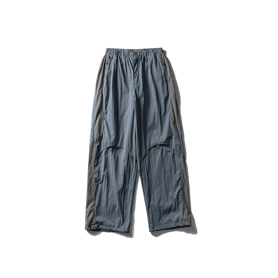 Blue-gray wide-leg pants with gray contrast side panels, elastic waist and curved knee seams, flat lay front view
