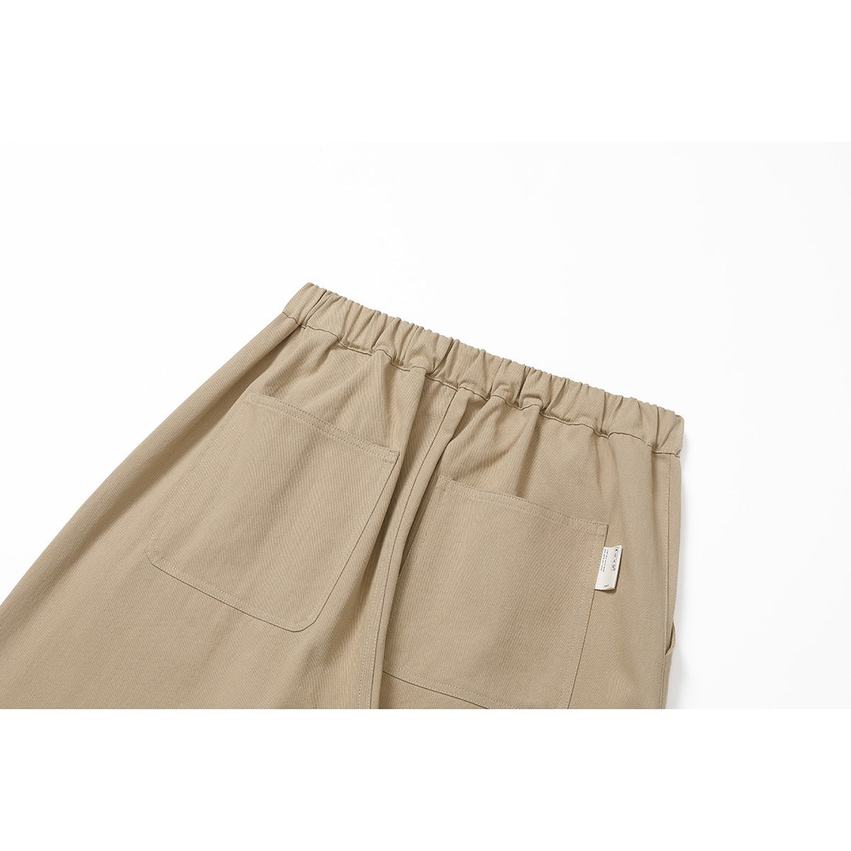 Close-up of the back of tan pants, showing an elastic waistband and two patch pockets.
