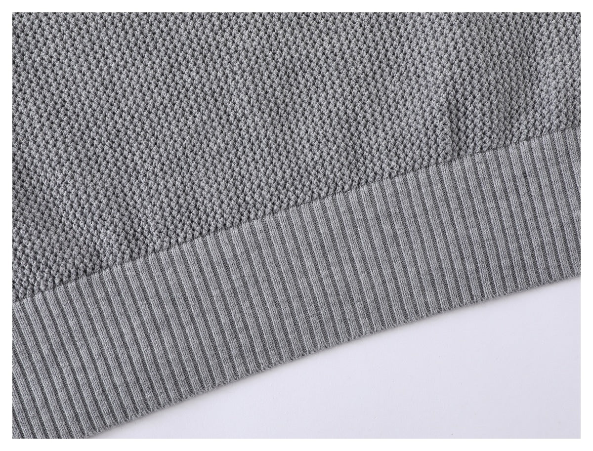 Close-up of the gray sweater's textured knit body and wide ribbed hem.