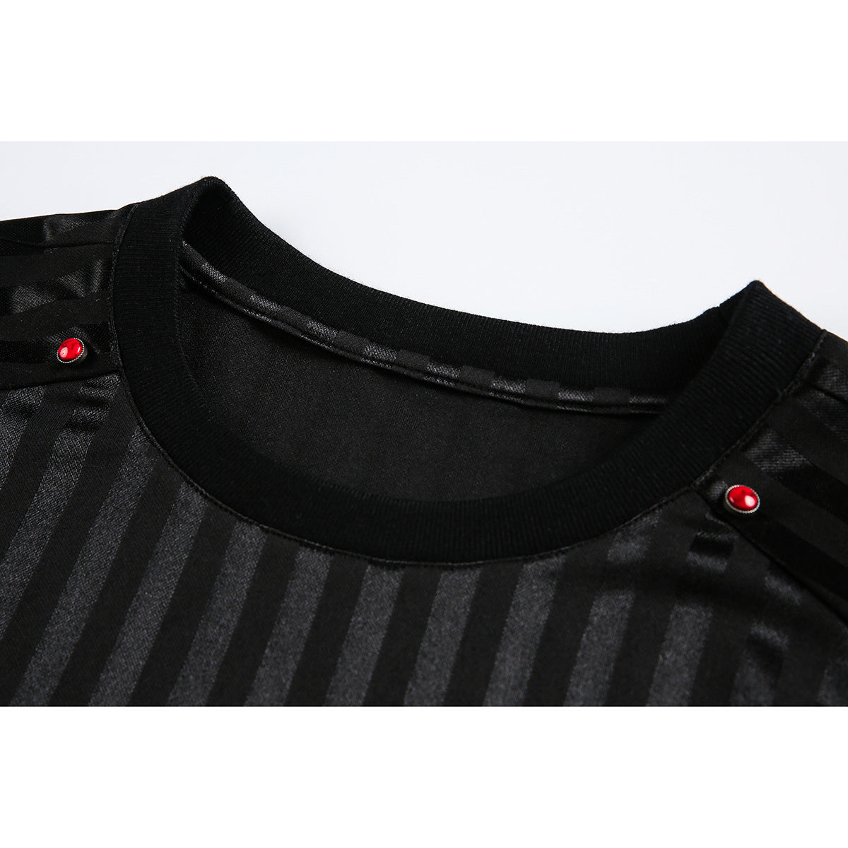 Close-up of a black top with subtle vertical stripes, a ribbed crew neckline, and small red shoulder buttons.