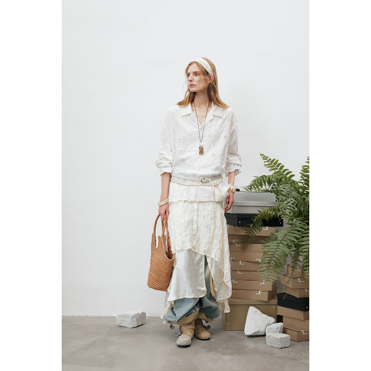 Full-length view of a model in a white eyelet blouse and layered white skirt over jeans.