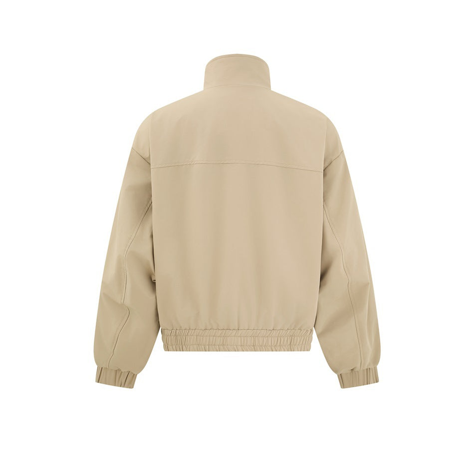 Back view of a beige jacket with a high collar, horizontal upper-back seam and gathered elastic hem and cuffs.