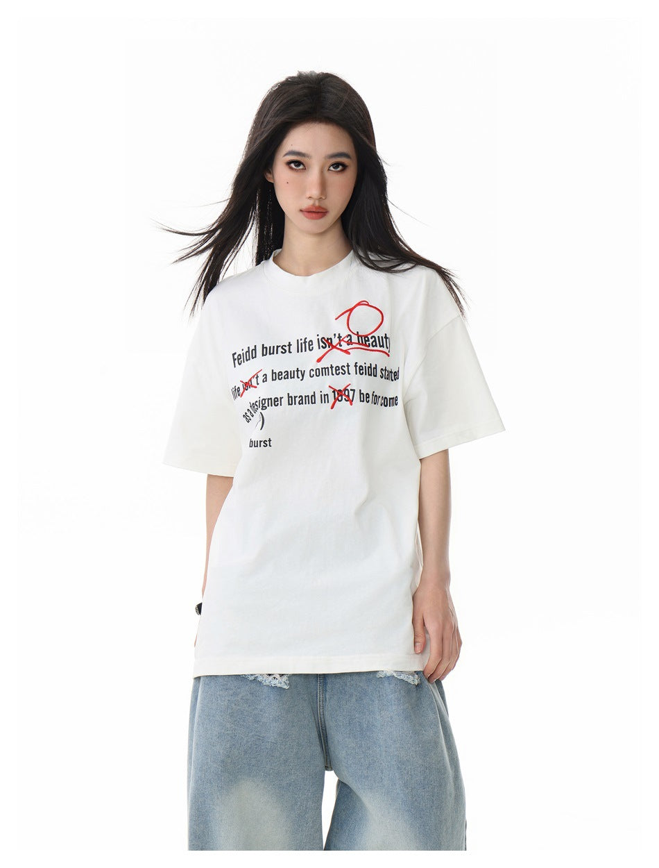 Closer front view of a model wearing an off-white oversized T-shirt with black text and red graphics, with light-wash jeans.
