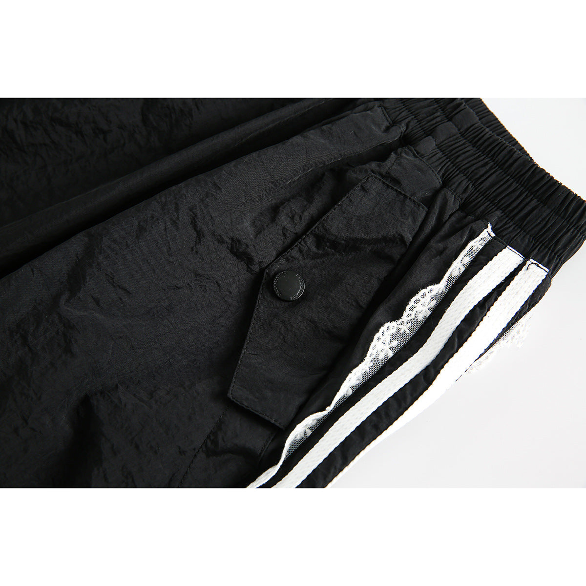 Close-up of a black skirt waistband and flap pocket with a button, white stripes, and lace trim.