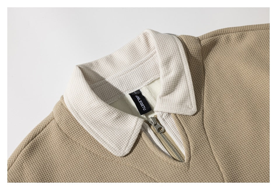 Close-up of the tan pullover’s textured fabric, cream collar and short metal zipper.