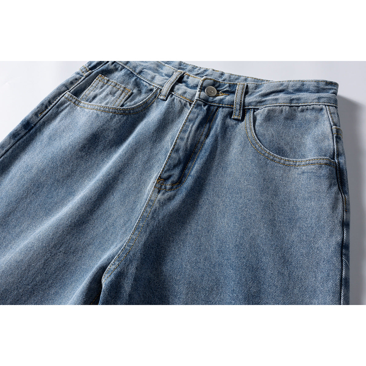 Close-up of light blue jeans showing the front waistband, button, belt loops, and pockets.