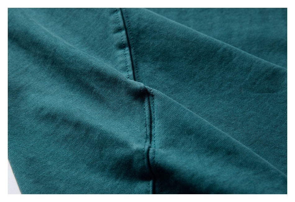 Close-up of a stitched seam on dark teal garment fabric.