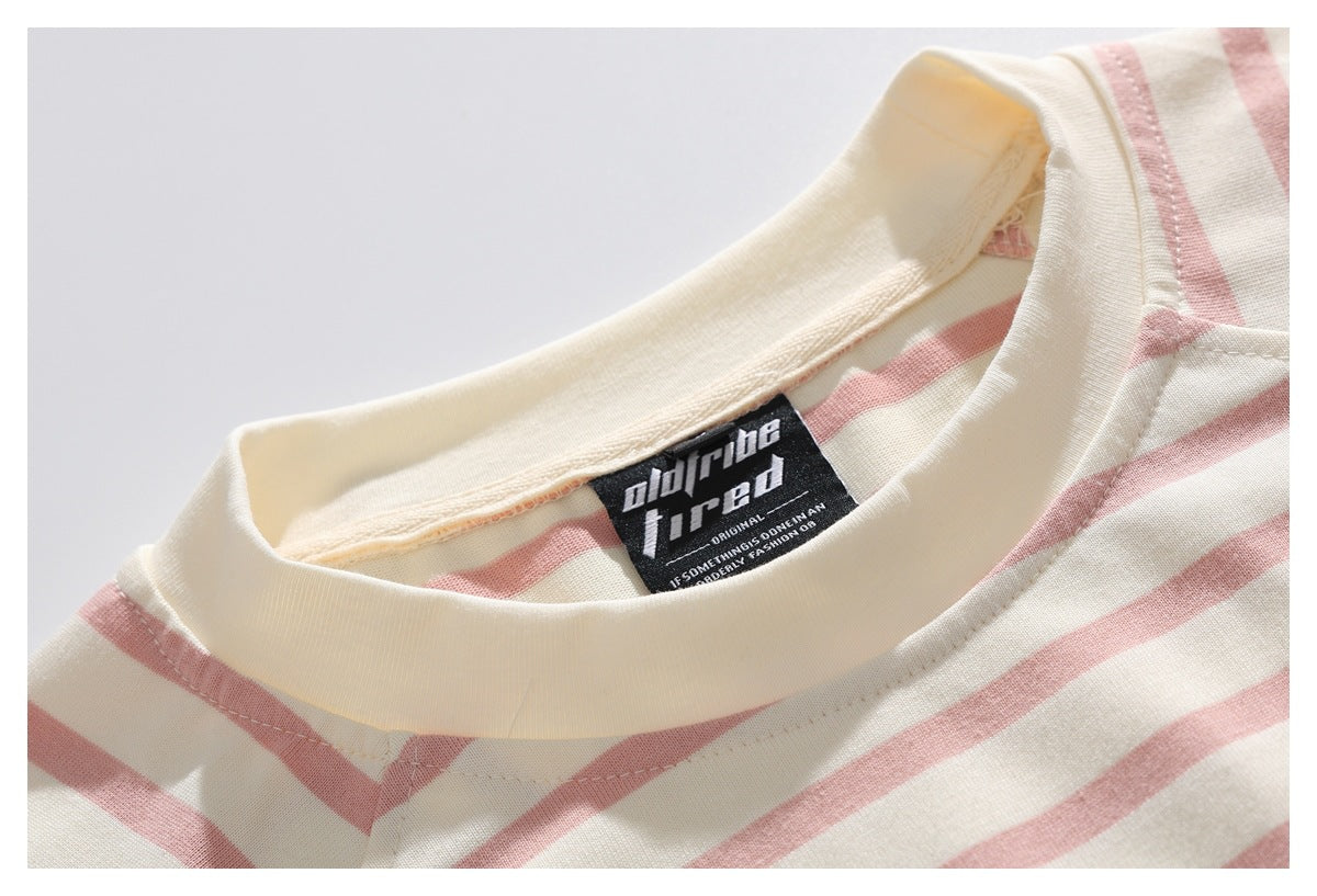 Close-up of the cream ribbed neckline and sewn black label on a cream shirt with dusty pink stripes.