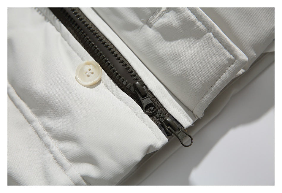 Close-up of a dark two-way zipper and button on a white jacket.