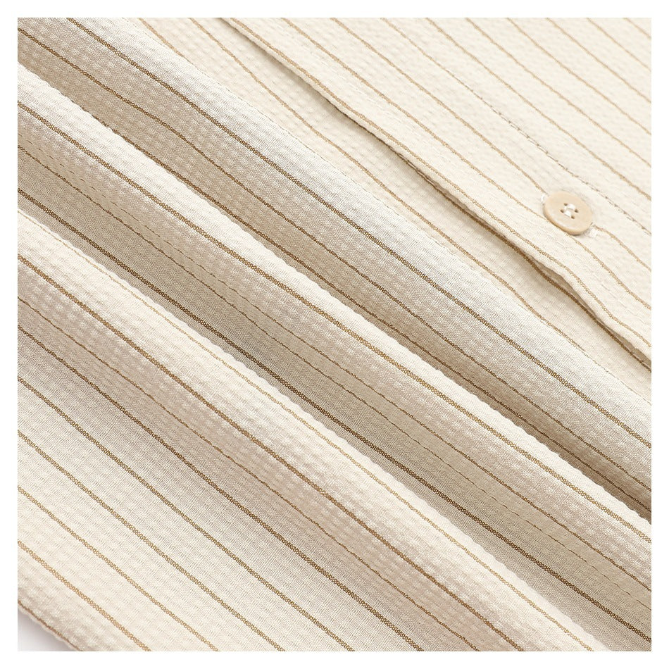 Close-up showing the cream shirt's textured fabric and fine tan stripes beside a button.
