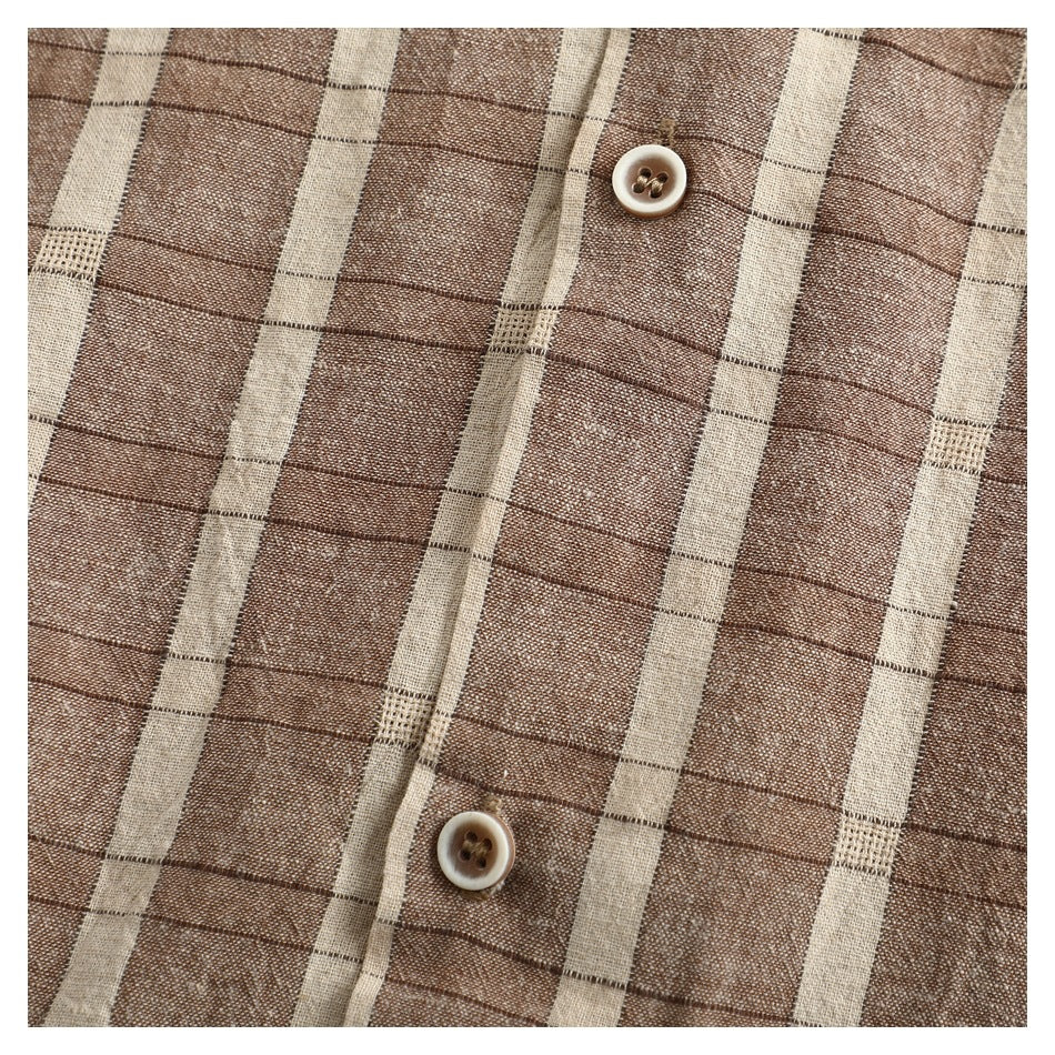 Close-up of the brown and cream plaid shirt's button placket and woven pattern.