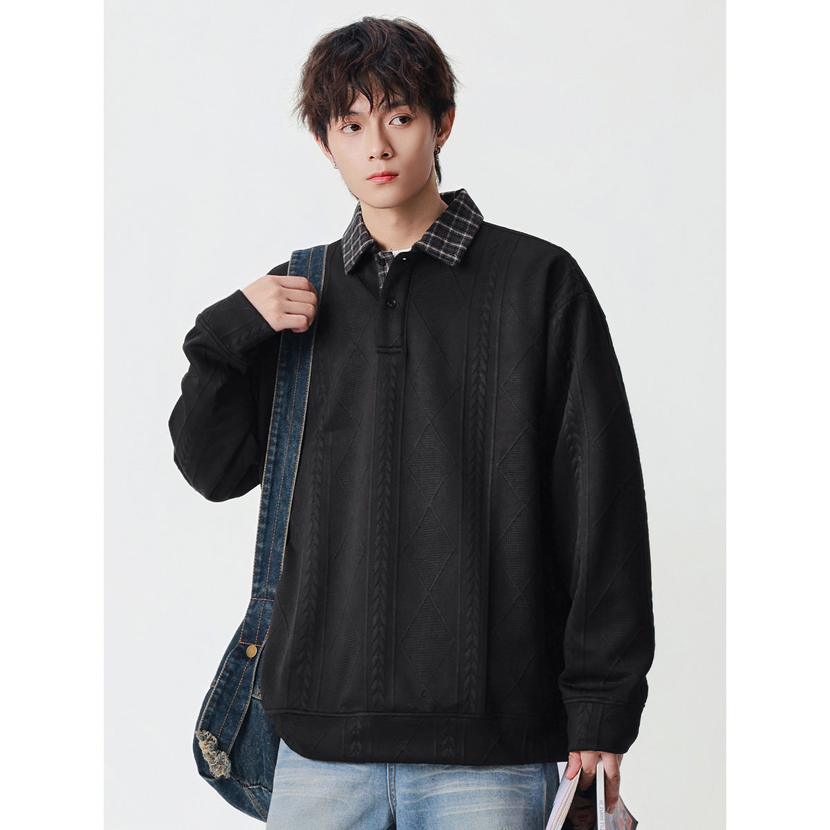 Model wearing a black oversized pullover with a dark plaid collar, button placket, and raised cable and diamond patterns.