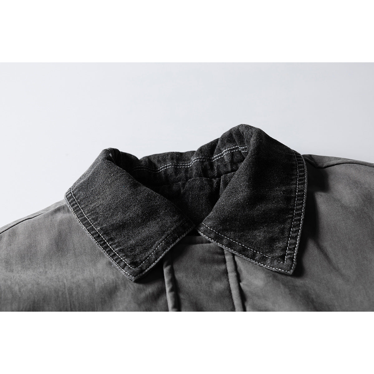 Close-up of a charcoal gray jacket with a contrasting black denim-style pointed collar and visible stitching.