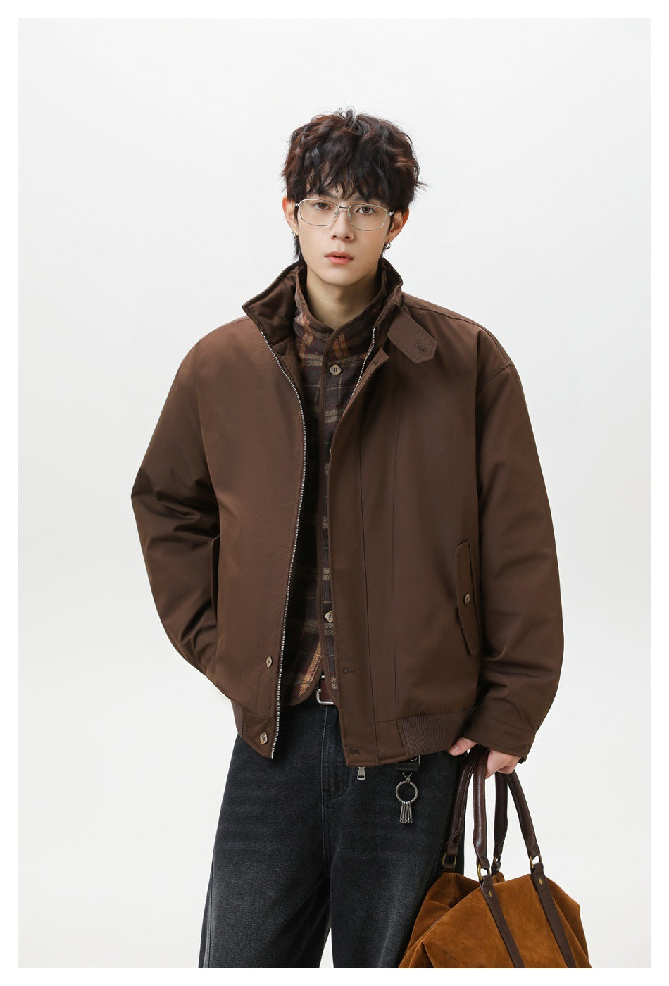 Model in a brown jacket with a raised collar, plaid inner layer, and zip front, shown from the waist up.