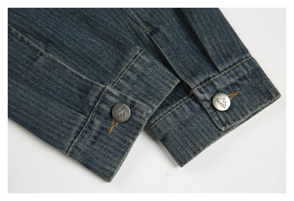Close-up of dark blue denim cuffs with contrast stitching and two engraved metal buttons.