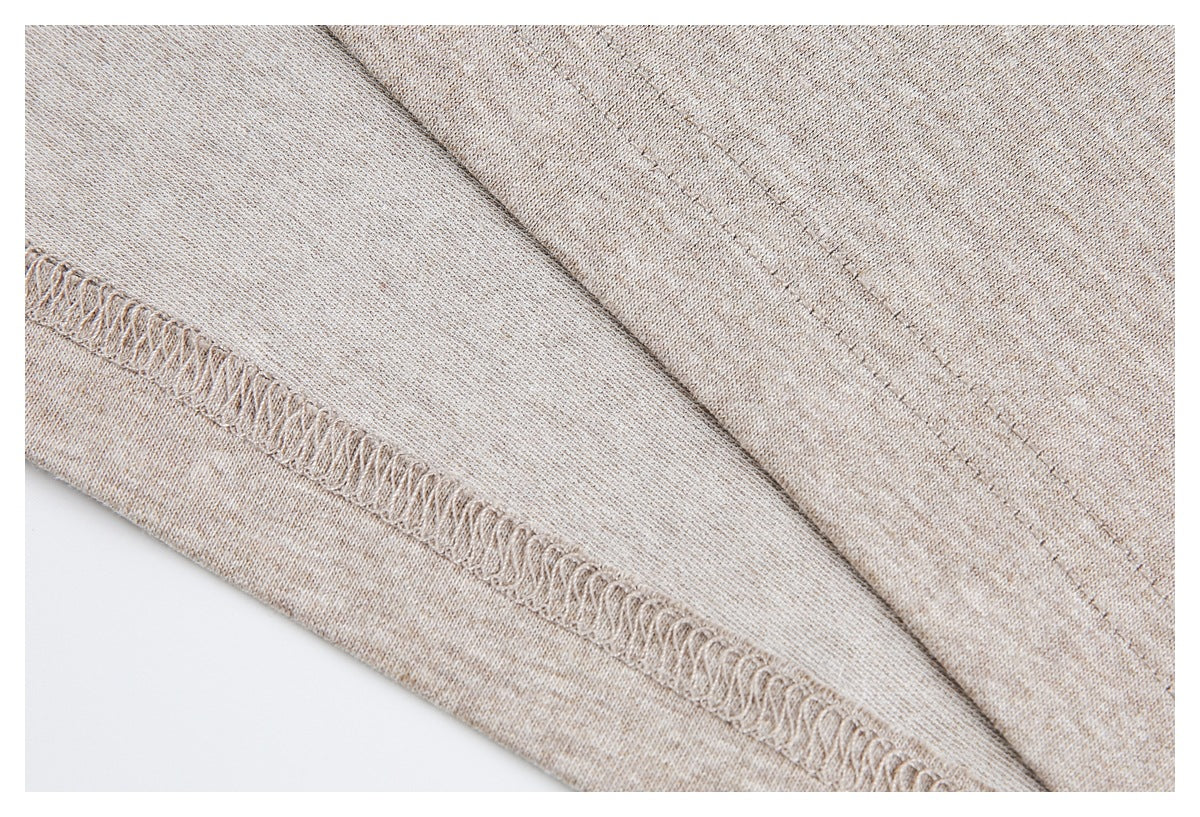 Inside close-up of beige heather knit fabric showing an overlocked hem seam and stitching.
