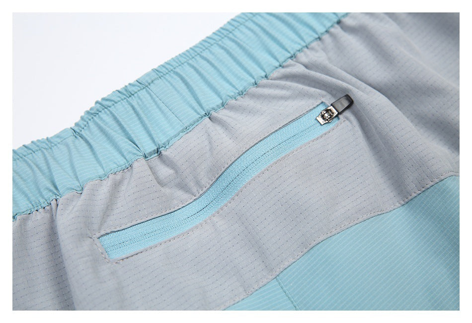 Close-up of the shorts' gray back panel and light blue zip pocket with a metal zipper pull.